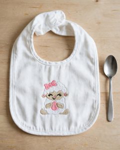 Lamb With Egg & Bow Machine Embroidery Design embroidered on a bib